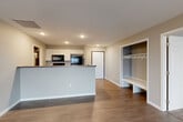 Located at 3500 S Grand Slam Ave in Sioux Falls, South Dakota, this well-designed two-bedroom, two-bathroom single-floor residence offers a comfortable and functional living experience. The open-concept kitchen and living room serve as the heart of the home, where wood-look plank flooring flows throughout and recessed lighting illuminates the space. The kitchen is equipped with white shaker cabinetry, dark countertops, a black electric range with over-the-range microwave, a stainless steel refrigerator, a dishwasher, and a peninsula with an integrated sink — ideal for both cooking and casual dining. The living area extends toward a sliding glass door that opens to a balcony, bringing in natural light and outdoor views. A charming built-in mudroom nook with a bench and coat hooks provides convenient storage near the entry. The spacious primary bedroom features neutral tones and connects to a walk-in closet with dual hanging rods and carpeted flooring. The second bedroom offers hard-surface flooring and ample wall space. Both bathrooms are finished with hardwood-style floors, vanities with mirrors, and well-lit fixtures, with one bath featuring a full tub-shower combo. A utility room completes this thoughtfully laid-out home.