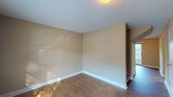 This two-floor home offers three bedrooms and one and a half bathrooms across a well-organized layout. The main level features wood-style flooring throughout the living areas, including a spacious living room bathed in natural light and a dining area with a sliding glass door that opens to an outdoor view. The galley-style kitchen is equipped with rich wood cabinetry, granite-style countertops, black appliances including an electric range, and a window that brings in natural light. A convenient half bathroom with a granite-style vanity completes the main floor. Upstairs, all three bedrooms are carpeted and feature ceiling fans. Two of the bedrooms include closets, and each room receives natural light through blinds-covered windows. The full bathroom on the upper level is well-appointed with a dual-sink vanity, rich wood cabinetry, a tall storage tower, granite-style countertops, and a shower-tub combination. Textured ceilings and neutral warm-toned walls are consistent throughout, creating a cohesive and functional living environment.