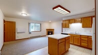 Located at 4532 Arrowhead Dr in Eau Claire, Wisconsin, this single-floor, 2-bedroom, 2-bathroom home offers a practical and comfortable layout. The open-concept kitchen and living area serves as the heart of the home, where warm oak cabinetry, a center island with white countertops, tile flooring, and a grid-panel ceiling light fixture define the kitchen space. Appliances include a refrigerator, electric range, and dishwasher. The living area flows naturally from the kitchen, featuring plush carpeting, a wood-trimmed gas fireplace, and a window that brings in natural light. Both bedrooms are carpeted and include windows with views of the surrounding greenery, with the primary bedroom offering a comfortable, well-proportioned layout. Four closets are distributed throughout the home for ample storage. The two bathrooms feature oak vanities with white countertops, tile flooring, and tub/shower combinations. A dedicated laundry area and a utility room with a water heater add functional convenience. A wooden deck off the main level overlooks a wooded backdrop and green lawn, providing a serene outdoor retreat. Baseboard heating is present throughout the home.