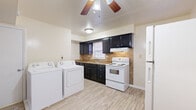 This two-story home offers a practical and functional layout across both levels. The kitchen is a standout space, featuring dark espresso cabinetry contrasted against a tile backsplash and laminate wood-style flooring. White appliances, including an electric range and refrigerator, are included, and a window above the sink provides natural light. Conveniently located adjacent to the kitchen is an in-unit laundry area with a full-size washer and dryer, adding everyday practicality to the home.

A dedicated dining area sits nearby, accented by two-tone walls and a ceiling fan overhead. The living areas on the lower level are carpeted and open in feel, with windows inviting natural light throughout.

A carpeted staircase with a dark metal railing connects the floors, featuring twisted baluster detailing for a subtle decorative touch. Upstairs, the bedrooms are generously sized, each featuring plush carpet, ceiling fans with light fixtures, and windows that bring in natural light. The soft blue-gray accent walls lend a calm, neutral tone to the sleeping areas.

The bathroom includes a full-size soaking tub with a shower, fully tiled surround in classic white, and a window for ventilation and natural light. Overall, the home presents a clean, functional living environment.
