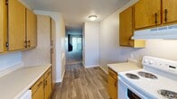 This 3-bedroom, 1-bathroom apartment in Wichita, Kansas offers a practical and comfortable single-floor layout. The kitchen is well-equipped with warm oak cabinetry extending from floor to ceiling, white countertops, a double sink, a white electric range, and a dishwasher. Durable wood-look flooring runs through the kitchen and hallway, providing a clean transition into the carpeted living areas. The spacious living room is a standout, featuring a freestanding black fireplace and a sliding glass door with vertical blinds that fills the room with natural light and provides access to an outdoor area. The generously sized primary bedroom includes a large closet and an adjoining walk-in closet, along with convenient access to the full bathroom. The two additional bedrooms are carpeted and each feature windows that bring in natural light, making them well-suited as guest rooms, a home office, or a child's room. The full bathroom is outfitted with a combination tub and shower and oak cabinetry for storage. Textured ceilings are consistent throughout the unit, and the overall layout is efficiently designed to maximize the available living space.