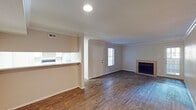 This single-story, 1-bedroom, 1-bathroom unit in Houston, TX (77060) offers a thoughtfully laid-out floor plan with a blend of practical finishes and comfortable living spaces throughout. The open living area is anchored by a tile-surround wood-burning fireplace and features rich, dark wood-look flooring that extends through the main living spaces. Crown molding adds a classic touch, while a windowed door allows natural light to brighten the room. The layout flows seamlessly from the entry toward the living area, where a pass-through counter connects to the kitchen, creating an open, airy feel. The galley-style kitchen is well-equipped with white cabinetry, a double-basin sink, light-speckled countertops, and a white electric range, providing ample storage and prep space. A dedicated laundry or utility area is accessible from the kitchen. The bedroom is carpeted for comfort, features a ceiling fan with light fixture, and receives natural light through a window with blinds. The full bathroom includes a tub/shower combination, vanity with light countertop, and wood-look flooring. Neutral wall tones and consistent flooring throughout give the space a clean, cohesive appearance well-suited for comfortable everyday living.