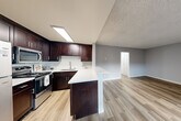 Located at 9404 Regent Street in the Palms neighborhood of Los Angeles, this one-bedroom, one-bathroom unit offers a thoughtfully laid-out single-floor plan. Warm hardwood-style flooring runs throughout the entire space, creating a cohesive and inviting atmosphere.

The open-concept kitchen and living area form the heart of the unit. The kitchen is equipped with rich dark espresso cabinetry, stainless steel appliances including a refrigerator, gas range, and microwave, as well as a bright white quartz countertop that extends into a peninsula — ideal for casual dining or meal prep. A skylight above the kitchen fills the space with natural light. The adjoining living area is spacious and bright, featuring a large window that brings in additional natural light and a wall-mounted AC unit for climate control.

The bedroom is a well-proportioned retreat with a large window, a textured ceiling, and dual mirrored sliding closet doors that add depth and functionality to the room.

The bathroom is clean and modern, featuring dark cabinetry with quartz countertops, a tub-shower combination with white tile surround, and a small window for natural ventilation. A connecting hallway ties all rooms together efficiently, completing this well-designed unit.