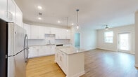 Located at 7045 Pine Forest Rd in Pensacola, FL, this single-story home offers three bedrooms, two bathrooms, and a thoughtfully designed open-concept layout. The kitchen serves as the heart of the home, showcasing crisp white shaker cabinetry, a classic subway tile backsplash, granite countertops, and a central island with globe pendant lighting overhead. Stainless steel appliances — including a refrigerator, range, microwave, and dishwasher — complete the space. Light-toned luxury vinyl plank flooring flows seamlessly from the kitchen into the living area, which features a ceiling fan and a glass-panel door that invites natural light. The spacious primary bedroom is carpeted for comfort, includes a ceiling fan, and connects to a private en-suite bathroom with a granite-topped vanity, a glass-enclosed shower, and direct access to a walk-in closet with wire shelving. The additional bedrooms are similarly carpeted, each equipped with ceiling fans and windows that let in ample natural light. A second full bathroom mirrors the refined finishes found throughout, with matching granite countertops and white cabinetry. A hallway connects the rooms cohesively, rounding out this clean, modern home.