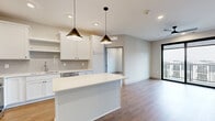 This well-appointed 2-bedroom, 2-bathroom unit in Ankeny, Iowa offers a thoughtfully designed open-concept layout with modern finishes throughout. The combined kitchen and living area serves as the heart of the home, anchored by a sleek white kitchen featuring shaker-style cabinetry, a subway tile backsplash, stainless steel appliances, and a central island with pendant lighting — ideal for both meal prep and casual dining. Warm-toned hardwood-style flooring flows seamlessly throughout the entire unit, complementing the clean, neutral color palette. The living area connects directly to a private balcony through large black-framed sliding glass doors, filling the space with natural light and offering exterior views. Both bedrooms are well-sized, with the primary bedroom providing a comfortable retreat. Large black-framed windows bring in additional natural light. Three closets, including a walk-in fitted with wire shelving systems, provide generous storage. The two bathrooms are finished with white vanity cabinetry, light countertops, and wood-look flooring, with one featuring a full tub-shower combination. A dedicated in-unit laundry area adds everyday convenience, completing this modern and functional home.