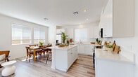 Located at 43501 Oleander Street in Lancaster, CA, this single-story home offers a well-designed layout with 2 bedrooms, 2 bathrooms, a dedicated office, and in-unit laundry. The open-concept kitchen and dining area serves as the heart of the home, featuring crisp white shaker cabinetry, light quartz countertops, a central island with bar seating, stainless steel appliances, and light wood-tone flooring. Multiple windows fill the space with natural light, creating a bright and airy atmosphere. The adjoining dining area provides easy access to the private outdoor patio, which includes a small turf area, concrete walkways, and block wall fencing — ideal for relaxing or entertaining. The bedrooms offer plush carpet flooring and window treatments, with the primary bedroom providing a comfortable and restful retreat. The bathrooms are finished in clean white tones, with one featuring a walk-in glass shower. The office is a quiet, carpeted room with a closet and natural light from a single window. A dedicated laundry area houses a stacked washer and dryer unit. Throughout, the home presents a cohesive, modern aesthetic with neutral tones and functional finishes.