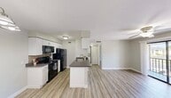 This thoughtfully designed 1-bedroom, 1-bathroom unit offers a comfortable and efficient layout spread across a single floor. Light-toned luxury vinyl plank flooring runs throughout the entire space, lending a clean, cohesive aesthetic to every room.

The open-concept kitchen and living area serves as the heart of the unit. The kitchen is equipped with white shaker-style cabinetry, dark granite-look countertops, a tile backsplash, and black appliances including a refrigerator, range, and over-the-range microwave. A peninsula with a built-in sink and additional counter space provides both functionality and a natural transition into the living area. A chandelier-style light fixture adds a decorative touch to the dining area, while the living room features a ceiling fan and a sliding glass door that opens to a balcony with pleasant outdoor views.

The bedroom is a well-sized, tranquil retreat with soft neutral walls, a window with natural light, and direct access to a dedicated closet. The full bathroom features white cabinetry, a dark countertop, and a tiled shower-tub combination with clean, simple finishes. A hallway connects the private areas of the unit efficiently. The overall ambiance is bright, neutral, and move-in ready.