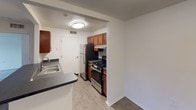 This single-floor unit is thoughtfully laid out to maximize functionality across its various living spaces. The floor plan, visible in the 3D model, reveals a well-organized arrangement of rooms connected by a central corridor.

The bedrooms are finished with plush grey carpeting and neutral cream-toned walls, lending a clean and versatile aesthetic. Each bedroom features at least one double-hung window that allows natural light to filter in, offering views of surrounding greenery. One bedroom includes direct access to a private bathroom, providing added convenience.

The kitchen is equipped with warm-toned wood cabinetry, dark laminate countertops, and stainless steel appliances including a gas range and refrigerator. Light wood-style flooring grounds the space, and a double-basin sink sits beneath upper cabinets for efficient storage. A pass-through opening connects the kitchen to the adjacent living area, enhancing the sense of openness.

The bathrooms are finished in crisp white, each featuring a tub and shower combination with brushed nickel fixtures, a vanity with mirror, and clean tile surrounds. The overall palette throughout the unit is neutral and cohesive, creating a bright, move-in ready environment.