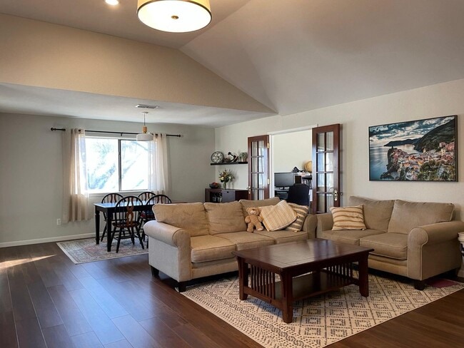 Bright, open living and dining space with vaulted ceilings and natural light. - 2401 Thistle Ct