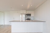 Located at 2737 Kipling Ave in Toronto's northwest end, this 2-bedroom, 1-bathroom unit offers a clean, modern design across a single floor. Light-toned laminate wood flooring runs throughout, complementing the crisp white walls and creating a bright, cohesive aesthetic.

The open-concept living room is bathed in natural light from a wide bank of windows that frame views of the surrounding greenery, with baseboard heating running beneath for year-round comfort. The kitchen is efficiently designed with white flat-panel cabinetry extending to the ceiling, a neutral-toned countertop with an integrated sink, and stainless steel appliances including a full-size refrigerator and dishwasher.

Both bedrooms are well-proportioned and naturally lit. The primary bedroom features a large window with outdoor views and a dedicated closet, while the second bedroom offers a clean, versatile space. Each room benefits from the same warm flooring and neutral palette found throughout the unit.

The bathroom is finished with grey tile flooring, a glass-enclosed walk-in shower with white subway tile walls and a mosaic tile base, and modern chrome fixtures. A utility room rounds out the layout, adding practical storage and functionality to the space.