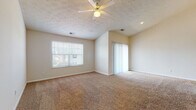 Located at 2688 Diamond Cut Dr. in Beavercreek, Ohio, this single-floor home offers a well-designed layout with a warm, neutral color palette throughout. The expansive living area is a standout feature, boasting soaring vaulted ceilings that amplify the sense of space, a ceiling fan with light fixture, textured ceilings, and plush wall-to-wall carpeting. Large windows dressed with blinds invite natural light, while sliding glass doors provide access to the outdoors. A pass-through opening connects the living area to adjacent spaces, enhancing the open feel of the floor plan. The kitchen is functionally appointed with warm honey-toned cabinetry, ample counter space, tile flooring, and includes a range with overhead microwave. A dedicated walk-in pantry with built-in shelving adds excellent storage. The bedrooms continue the home's consistent aesthetic with soft carpeting, textured ceilings, and windows that bring in natural light. The bathroom features a full tub/shower combination with clean white fixtures and tile flooring. Throughout the home, consistent trim work, neutral wall tones, and thoughtful details contribute to a cohesive and comfortable living environment.