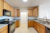 Located at 4645 Daisy Reid Ave in Woodbridge, VA, this 2-bedroom, 2-bathroom residence offers a well-organized single-floor layout designed for comfortable everyday living. The kitchen is a functional highlight, featuring warm honey-toned wood cabinetry with ample storage, granite-style countertops, tile flooring, and black appliances including a refrigerator, electric range, and built-in microwave. A stacked washer and dryer unit is conveniently integrated into the kitchen area, adding in-unit laundry functionality. The combined kitchen and living area flows naturally, with the living room finished in plush neutral carpeting and a sliding glass door that invites natural light and provides outdoor access. The spacious primary bedroom is a comfortable retreat, also carpeted, with a generous closet and access to a private en-suite bathroom featuring a glass-enclosed shower and tile floors. The second bedroom is well-proportioned with soft carpet, a large window offering outdoor views, and easy access to the second full bathroom, which includes a vanity with warm wood cabinetry and a mirror. Clean white walls throughout lend the home a bright, neutral palette, while six-panel doors add a classic touch. A dedicated utility room rounds out the practical amenities of this thoughtfully laid-out home.