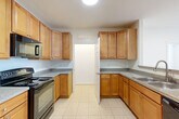 Located at 4645 Daisy Reid Ave in Woodbridge, VA, this 2-bedroom, 2-bathroom residence offers a well-organized single-floor layout designed for comfortable everyday living. The kitchen is a functional highlight, featuring warm honey-toned wood cabinetry with ample storage, granite-style countertops, tile flooring, and black appliances including a refrigerator, electric range, and built-in microwave. A stacked washer and dryer unit is conveniently integrated into the kitchen area, adding in-unit laundry functionality. The combined kitchen and living area flows naturally, with the living room finished in plush neutral carpeting and a sliding glass door that invites natural light and provides outdoor access. The spacious primary bedroom is a comfortable retreat, also carpeted, with a generous closet and access to a private en-suite bathroom featuring a glass-enclosed shower and tile floors. The second bedroom is well-proportioned with soft carpet, a large window offering outdoor views, and easy access to the second full bathroom, which includes a vanity with warm wood cabinetry and a mirror. Clean white walls throughout lend the home a bright, neutral palette, while six-panel doors add a classic touch. A dedicated utility room rounds out the practical amenities of this thoughtfully laid-out home.