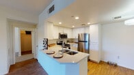 This single-floor residence offers a thoughtfully designed layout that balances functionality and comfort throughout. The kitchen serves as a standout feature, showcasing crisp white shaker cabinetry, light quartz countertops, and a full suite of stainless steel appliances including a gas range, over-the-range microwave, and refrigerator. A peninsula with an integrated double-basin sink provides additional prep space and casual seating, creating a natural connection to the open living area. The living room is finished with warm wood-look flooring and receives natural light through a sliding glass door that opens directly to a private patio, offering a seamless indoor-outdoor flow. Two bedrooms feature plush carpet flooring, ceiling fans or ample natural light from windows with blinds, and generous closet access. The two full bathrooms are finished in a clean, neutral palette — one featuring a tub-shower combination with tiled surround, and the other with a single-sink vanity with white cabinetry and a tub-shower combo. Additional highlights include in-unit laundry access, recessed lighting throughout the kitchen and living spaces, and a consistent neutral color scheme that lends the home a bright, move-in-ready ambiance.