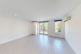 Located at 42 N Beacon St, Unit 203 in Boston's Allston neighborhood, this thoughtfully designed unit offers a clean, modern aesthetic throughout. Light-toned hardwood-style flooring runs continuously across the space, complementing the crisp white walls and recessed lighting that create a bright, airy atmosphere.

The living room is the heart of the unit, featuring sliding glass doors that open to a private balcony, flooding the space with natural light and offering pleasant outdoor views of surrounding greenery. A wall-mounted mini-split system provides efficient climate control. Built-in cabinetry adds functional storage without compromising the open feel of the room.

The kitchen is well-appointed with high-gloss white cabinetry, white quartz countertops, and a classic subway tile backsplash. Stainless steel appliances — including a refrigerator, electric range, over-the-range microwave, and dishwasher — complete this modern culinary space, which flows seamlessly into the main living area.

The bathroom features large-format tile flooring, a subway-tiled tub-shower combination, a warm wood-toned vanity with a white countertop, and a well-lit mirror. The entrance provides a practical transition into the unit with convenient access to the main living and kitchen areas.