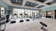 This single-story fitness and recreation facility is designed with a cohesive coastal aesthetic, featuring soft aqua and slate blue walls, crisp white trim, and coffered ceilings with recessed lighting throughout. The main fitness floor is expansive and open, with large-format tile flooring and floor-to-ceiling windows that invite abundant natural light and views of surrounding tropical landscaping. The space is comprehensively equipped with a full array of cardio machines—including treadmills, ellipticals, and rowing equipment—alongside cable machines, a dumbbell rack, benches, and various strength-training stations. Ceiling-mounted televisions and full-length mirrors enhance the workout environment. An adjoining studio room features light hardwood floors, a tray ceiling, spin bikes, stability balls, and additional cardio equipment, offering a dedicated space for group or individual training. A separate children's playroom provides a vibrant, engaging environment with whimsical ocean-themed murals, soft carpet tiles, a wall-mounted television, educational toys, and child-sized furniture. The common entry area features large-format tile, a built-in water fountain alcove with storage cabinetry, and interior windows connecting to the playroom, ensuring visibility and convenience for caregivers.
