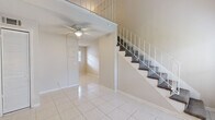 Located at 1606 King Street in Jacksonville, FL, this two-story residence offers a thoughtfully organized layout spread evenly across two floors. The main level welcomes you with a bright, open living area featuring gleaming large-format white tile flooring and soaring ceilings that lend an expansive, airy feel. Abundant natural light filters through multiple windows, while a ceiling fan keeps the space comfortable. A carpeted staircase with a white metal railing provides an architectural focal point as it connects the two levels. The kitchen on the main floor is equipped with full-height white cabinetry, ample granite-style countertops, a stainless steel range, and a single-basin sink — offering both style and functionality. Ascending to the upper level, the generous primary bedroom features warm wood-look laminate flooring, a shiplap ceiling, ceiling fan, and a wall sconce, creating an inviting retreat. A sliding-door closet provides practical storage, and the adjacent full bathroom showcases a tiled walk-in shower with a decorative accent border, pedestal sink, and clean, modern finishes. The overall palette throughout the home is neutral and light, lending a clean, move-in-ready aesthetic to this efficient Jacksonville residence.
