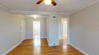 This single-floor, 2-bedroom, 1-bathroom home delivers a comfortable and functional layout across a well-proportioned footprint. Warm hardwood flooring flows consistently throughout the living areas and bedrooms, lending a sense of continuity and character to the space. Crown molding and ceiling fans are present throughout, adding classic detail and practical comfort.

The main living area is bright and open, with multiple doorways connecting to the rest of the home. A central hallway provides efficient access to all rooms. Both bedrooms are generously sized, each featuring hardwood floors, ceiling fans with light fixtures, crown molding, and multiple windows that invite abundant natural light and views of the surrounding greenery. The dual-window configurations in each bedroom create an airy, well-lit atmosphere.

The kitchen is bright and efficient, featuring white cabinetry, ample counter space, a stainless steel sink, and a pair of windows that fill the room with natural light. The full bathroom is clean and straightforward, finished in white tile with a full-size tub and shower combination, a toilet, and a window for natural ventilation. The overall aesthetic throughout the home is clean and neutral, with light gray walls providing a versatile backdrop ready for personalization.