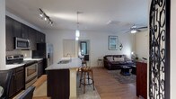 This single-story residence offers a thoughtfully designed open-concept layout that seamlessly connects the kitchen, dining, and living areas. The kitchen is outfitted with dark espresso cabinetry, granite countertops, a tile backsplash, stainless steel appliances including a French door refrigerator and built-in microwave, and a peninsula with bar seating. Pendant and track lighting illuminate the space, while wood-style flooring flows throughout the main living areas.

Adjacent to the kitchen, a dedicated dining nook accommodates a round glass-top table and seating for four, accented by framed wall art. The living room features a ceiling fan, natural light from a large window with outdoor views, and wood-style flooring underfoot.

Two bedrooms offer plush carpeting, ceiling fans, and generous natural light through large windows. One bedroom includes a spacious walk-in closet fitted with wire shelving. The bathroom features a soaking tub with tile surround. A dedicated laundry area houses a full-size washer and dryer, adding everyday convenience to this well-rounded residence.