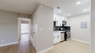 This 2-bedroom, 2-bathroom unit offers a thoughtfully designed single-floor layout with modern updates throughout. Light-toned luxury vinyl plank flooring runs continuously through all living areas, lending a clean, cohesive look to the space.

The kitchen is a standout feature, equipped with white shaker cabinets accented by matte black hardware, a bold dark hexagonal tile backsplash, light quartz countertops, and a full suite of stainless steel appliances including a gas range, microwave, dishwasher, and refrigerator.

Both bedrooms are comfortably proportioned and finished with ceiling fans and natural light from large windows fitted with blinds. The primary bedroom includes a built-in closet with shelving, accessed through stylish sliding barn doors with matte black hardware — a detail echoed in the second bedroom as well.

The bathrooms are elegantly finished with marble-style white tile featuring subtle grey veining. One bathroom includes a glass-enclosed walk-in shower with a floating wood-toned vanity and a backlit mirror, while the second features a soaking tub and shower combination with a matte black rainfall showerhead and fixtures.

The overall aesthetic is modern and cohesive, combining neutral warm-grey tones, black accents, and light wood flooring for a fresh, updated feel throughout.