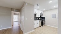 This 2-bedroom, 2-bathroom unit offers a thoughtfully designed single-floor layout with modern updates throughout. Light-toned luxury vinyl plank flooring runs continuously through all living areas, lending a clean, cohesive look to the space.

The kitchen is a standout feature, equipped with white shaker cabinets accented by matte black hardware, a bold dark hexagonal tile backsplash, light quartz countertops, and a full suite of stainless steel appliances including a gas range, microwave, dishwasher, and refrigerator.

Both bedrooms are comfortably proportioned and finished with ceiling fans and natural light from large windows fitted with blinds. The primary bedroom includes a built-in closet with shelving, accessed through stylish sliding barn doors with matte black hardware — a detail echoed in the second bedroom as well.

The bathrooms are elegantly finished with marble-style white tile featuring subtle grey veining. One bathroom includes a glass-enclosed walk-in shower with a floating wood-toned vanity and a backlit mirror, while the second features a soaking tub and shower combination with a matte black rainfall showerhead and fixtures.

The overall aesthetic is modern and cohesive, combining neutral warm-grey tones, black accents, and light wood flooring for a fresh, updated feel throughout.