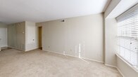 Located at 1046 Lake Ave in Metairie, Louisiana, this 2-bedroom, 3-bathroom single-story home offers a practical and comfortable layout with neutral tones and carpet flooring throughout the living areas. The open-concept living, dining, and kitchen area forms the heart of the home, featuring a peninsula counter with a pendant light overhead that separates the carpeted dining and living space from the tiled kitchen. The galley-style kitchen is equipped with warm wood cabinetry, light countertops, a double stainless steel sink, and white appliances including a range and refrigerator. A pantry provides additional storage convenience. The spacious primary bedroom features dual closets, a ceiling fan with light fixture, and connects to a bathroom with a vanity and a separate tub/shower room. The second bedroom is similarly sized, also appointed with a ceiling fan, multiple closets, and natural light from a window. Both bedrooms offer generous closet space, complemented by a remarkable total of seven closets throughout the home. The three bathrooms include tub/shower combinations with tiled surrounds. The hallway connects the private quarters to the shared spaces, and the overall palette of warm beige walls and light carpet creates a clean, move-in-ready atmosphere.