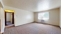 Located at 510 N State Rd in Medina, Ohio, this single-floor unit offers a practical and comfortable layout across several well-defined living spaces. The main living area is generously sized, featuring wall-to-wall carpeting, neutral cream-toned walls, a textured ceiling, and a large window with vertical blinds that allows ample natural light to filter in. A window-mounted air conditioning unit and baseboard heating provide year-round climate control. An additional carpeted room features a charming bay-style window with a built-in sill and a ceiling fan, adding character and outdoor views of the surrounding neighborhood. The kitchen is outfitted with warm oak cabinetry, granite-toned countertops, hardwood flooring, and includes a white electric range and refrigerator, offering functional storage and workspace. A hallway connects the main areas and includes a double-door closet, providing convenient storage. The bathroom is finished with hardwood flooring, a full tub-shower combination, a wood-toned vanity with a white countertop, and a mirrored medicine cabinet. Throughout the unit, the consistent use of warm wood tones, neutral walls, and carpeted floors creates a cohesive and inviting atmosphere.