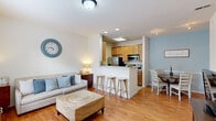 Located at 6806 Drayson Dr in Richmond, VA, this two-story home is thoughtfully laid out across two equally sized floors. The main level features an open-concept living, dining, and kitchen area bathed in natural light from large windows. The kitchen is well-appointed with warm wood cabinetry, stainless steel appliances including a refrigerator, electric range, and microwave, and a peninsula with bar seating that seamlessly connects to the dining area. Light hardwood flooring runs throughout the main level, enhancing the bright and airy feel. A staircase with a classic wood banister leads to the upper level, where the generously sized primary bedroom awaits, complete with plush carpeting, a ceiling fan, multiple windows with natural light, and ample room for a full bedroom suite. The bedroom is complemented by a spacious walk-in closet fitted with wire shelving for organized storage. Two bathrooms serve the home — one on each floor — with the upper bathroom featuring a wood-toned vanity and a bathtub. A convenient half bath with angled ceilings is also present. The home's neutral color palette and clean finishes create a warm, welcoming ambiance throughout.