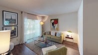 Located at 950 NW 214th Street in Miami Gardens, Florida, this single-story residence offers a well-designed layout with comfortable living spaces throughout. The living room is a welcoming area featuring wood-style flooring, a textured ceiling, and a large sliding glass door dressed with vertical blinds that invite abundant natural light and provide access to the outdoors. Adjacent to the living room, the dining area offers an intimate setting, complete with a full-length mirror that enhances the sense of space. The kitchen is thoughtfully appointed with white cabinetry, granite-style countertops, a decorative tile backsplash, and black appliances including a range and dishwasher. The space includes two bedrooms, both featuring plush carpeting, natural light from windows with curtains, and generous closet space. The primary bedroom includes a walk-in closet with louvered doors and a dedicated vanity area. Two bathrooms serve the residence — one featuring a shower-tub combination with white tile surround, and the other featuring a glass-enclosed stand-up shower and granite-topped vanity — both with warm wood-style flooring. Overall, the space presents a functional and comfortable layout well-suited for everyday living.