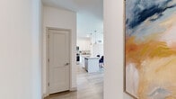 This well-designed single-floor residence combines modern finishes with a clean, contemporary aesthetic. Light wood-look flooring flows throughout the main living areas, anchoring the open layout and connecting each space seamlessly. The kitchen is a standout feature, showcasing white shaker cabinetry that reaches to the ceiling, granite countertops, stainless steel appliances including a range and built-in microwave, and a central island with seating — all illuminated by stylish pendant lighting overhead. Adjacent to the kitchen, the dining area accommodates a round table with ample room, while a soft blue accent wall adds a calm, distinctive character that carries into the living room. The living room is bright and inviting, featuring large windows that welcome natural light and provide views to the outdoors, complemented by a ceiling fan and direct access to an exterior door. The bedroom is generously sized with plush carpeting, large windows, a ceiling fan, and access to a spacious walk-in closet outfitted with multi-tiered wire shelving. The bathroom offers a clean, functional design with white cabinetry, granite countertops, an undermount sink, and a shower with a curtain enclosure. Thoughtful details such as decorative artwork and recessed lighting enhance the overall ambiance throughout.