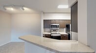 Located in Fort Worth, TX, this well-appointed residence offers four bedrooms and two bathrooms spread across two floors. The kitchen is a standout feature, showcasing rich dark wood cabinetry, granite-style countertops, stainless steel appliances including a range, microwave, and refrigerator, and hardwood-style flooring. A breakfast bar provides additional prep and dining space, seamlessly connecting the kitchen to the living area. The living room impresses with soaring vaulted ceilings, a ceiling fan, plush carpeting, and a tile-surround fireplace that serves as an elegant focal point. Natural light filters in through windows with blinds. The four bedrooms are carpeted and equipped with ceiling fans, offering comfortable, functional spaces. The primary bedroom provides a generous footprint for a full furniture arrangement. The two bathrooms are clean and functional, each featuring dark vanity cabinetry with stone-style countertops; at least one includes a full tub-shower combination with white tile surround. A dedicated in-unit laundry space houses a full-size washer and dryer with overhead wire shelving. The entrance hallway leads efficiently through the layout, which also includes a closet for additional storage. A private balcony offers open views of the surrounding community and sky.