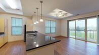 This single-floor residence is thoughtfully designed with a cohesive blend of functional finishes and open layouts. The kitchen is fully equipped with stainless steel appliances, including a range, built-in microwave, and refrigerator, all complemented by rich dark granite countertops and light maple cabinetry. A peninsula with an undermount sink extends into the living area, topped with pendant lighting that adds a stylish focal point. The kitchen also benefits from natural light through a dedicated window.

The open-concept living and dining area features warm hardwood-style flooring and a distinctive tray ceiling fitted with a ceiling fan. Large windows and sliding glass doors lead to a private balcony with open views of the surrounding landscape, filling the space with abundant natural light. The seamless flow between the kitchen and living area makes the layout feel expansive and inviting.

The bedroom offers plush carpeting, a ceiling fan, and a bright window, creating a comfortable and restful environment. The bathrooms are finished consistently with the home's design, featuring dark granite countertops, light maple vanity cabinetry, framed mirrors, tile flooring, and a shower-tub combination. Throughout the residence, neutral tones and quality finishes create a clean, modern ambiance.