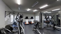 Located at 111 Springview Ln in Summerville, South Carolina, this fitness center offers a well-equipped, single-floor workout facility designed to support a range of exercise routines. The space is illuminated by multiple overhead fluorescent light fixtures mounted to a smooth ceiling, ensuring bright, consistent lighting throughout the room.

The fitness floor is finished with durable rubber flooring, providing both safety and comfort during workouts. Cardio equipment takes center stage, with multiple treadmills featuring integrated display screens and an elliptical cross-trainer positioned for easy access. A multi-station strength training machine is situated along one wall, complete with a weight stack and an exercise reference chart, catering to a variety of resistance training exercises.

Full-length mirrors line one wall, creating a sense of expanded space while allowing users to monitor their form during workouts. Natural light filters in through multiple windows fitted with horizontal blinds, complementing the artificial lighting. The walls are finished in a neutral gray tone, contributing to a clean and focused atmosphere. The overall layout is organized and functional, providing an accessible and practical environment for residents looking to maintain an active lifestyle.