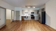 Located at 1000 Comet Dr in New Bern, NC, this single-floor residence offers a well-designed layout with a clean, modern aesthetic throughout. The open living area is anchored by warm hardwood-style flooring and illuminated by track lighting, creating a bright and welcoming atmosphere. French doors lead to a private balcony, bringing in abundant natural light and views of the surrounding greenery.

The kitchen is thoughtfully appointed with gray shaker-style cabinetry, granite countertops, a white subway tile backsplash, and a full suite of stainless steel appliances including a refrigerator, range, microwave, and dishwasher. A built-in wine rack adds a distinctive decorative touch.

The bedrooms feature plush wall-to-wall carpeting and ceiling fans with light fixtures, contributing to a comfortable and restful environment. Windows with blinds allow for natural light and outdoor views. The bathroom includes a granite-topped vanity with gray cabinetry and a tiled walk-in shower, finished with brushed nickel hardware throughout. Additional cabinetry provides practical storage. The overall design balances functional living with tasteful, contemporary finishes.