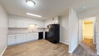Located at 110 Urban St in Bloomington, Illinois, this single-floor unit offers a clean, modern aesthetic with consistent wood-look flooring flowing throughout every room. The kitchen is a standout feature, equipped with crisp white shaker-style cabinetry, granite-look countertops, and a full suite of black appliances including an electric range, refrigerator, and dishwasher. A range hood and under-cabinet lighting add practicality, while the open layout creates a seamless connection to the living area, making the space feel open and functional. The living area is generously sized, bathed in natural light, and opens directly to the kitchen, lending an airy, connected feel to the main living space. The bedroom includes a built-in closet with a hanging rod, offering practical storage, and features the same wood-look flooring that ties the space together cohesively. The bathroom is neatly finished with a white vanity topped with a granite-look countertop, a tub/shower combination, and wood-look flooring that extends the home's consistent style. Neutral gray wall tones and textured ceilings complete the interior throughout, creating a calm and move-in-ready environment.