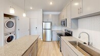 Located at 5409 Commonwealth Centre Pkwy in Midlothian, Virginia, this single-floor unit offers a clean, contemporary design highlighted by light hardwood-style flooring and crisp white walls that carry consistently throughout the space. The open-concept layout connects the kitchen and living area seamlessly, creating a bright and functional central gathering space. Multiple windows allow abundant natural light to fill the living area, which features a ceiling fan and direct sightlines to the kitchen.

The kitchen is well-appointed with grey shaker-style cabinetry, granite countertops, a herringbone tile backsplash, and stainless steel appliances including a range, microwave, and refrigerator. A peninsula with an undermount sink and pendant lighting above adds both workspace and visual definition between the kitchen and living area.

The bedrooms are comfortably sized, each with light-toned flooring, neutral walls, and windows providing natural light and outdoor views. Ceiling fans are present in the main living and bedroom areas.

Two bathrooms mirror the unit's consistent design language, each featuring grey vanity cabinetry, granite countertops, and light flooring. One bathroom includes a walk-in glass-enclosed shower, while the other offers a shower-tub combination, both finished with brushed nickel hardware throughout.
