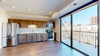 This contemporary single-floor residence offers a thoughtfully designed layout that balances comfort and modern style throughout. The kitchen serves as a focal point, showcasing rich dark wood cabinetry paired with a striking mosaic tile backsplash, light quartz countertops, and a full suite of stainless steel appliances including a refrigerator, range, microwave, dishwasher, and double-basin sink. Recessed lighting illuminates the space, which flows seamlessly into the open living area finished with warm wood-look luxury vinyl plank flooring. A floor-to-ceiling sliding glass door floods the main living space with abundant natural light and opens to a private balcony, offering impressive views of the surrounding city skyline. The bedroom areas are spacious and neutrally finished, with clean lines and wood-look flooring carried throughout. A walk-in closet with wire shelving systems provides generous, well-organized storage. The bathroom features a full tub-shower combination with white tile surround, chrome fixtures, and light tile flooring, maintaining a clean and functional aesthetic. Neutral warm-toned walls and consistent modern finishes create a cohesive, move-in-ready ambiance throughout the entire residence.