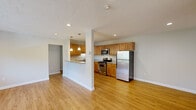 Located at 15 Dolores Ave in Waltham, MA, this one-bedroom, one-bathroom residence offers a well-organized, efficiently designed layout across a single floor. Light hardwood-style flooring runs throughout, creating a warm and cohesive feel in every room.

The open-concept kitchen and living area serves as the heart of the home. The kitchen is outfitted with warm honey-toned cabinetry, granite countertops, stainless steel appliances including a gas range, built-in microwave, and refrigerator, and a peninsula with pendant lighting that seamlessly connects to the living space. The living area features recessed lighting, a wall-mounted air conditioning unit, and a wide window framing views of the surrounding greenery, filling the space with natural light.

The bedroom is a comfortable, well-proportioned room with its own window providing additional natural light and outdoor views, along with baseboard heating and a closet. An entry hallway offers additional closet storage, providing practical everyday convenience.

The bathroom is appointed with floor-to-ceiling stone-look tile surrounds in the tub/shower combination, accented by a decorative mosaic tile border, giving the space a clean, polished finish. Overall, the residence presents a bright and functional living environment in a convenient Waltham location.