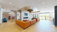 Located at 2225 Chester St in Aurora, Colorado, this thoughtfully designed single-floor amenity space offers a seamless blend of modern aesthetics and functional comfort across three distinct areas.

The hallway serves as an inviting entry point, transitioning guests into the heart of the space with warm wood-paneled walls, herringbone light hardwood flooring, and a curved, wood-clad ceiling detail that adds architectural dimension. The lounge area features bold tangerine leather sectional sofas accented with teal throw pillows, centered around a sleek linear fireplace with a textured tile surround and a wall-mounted TV. A striking round art piece and contemporary line-art portraits add personality, while floor-to-ceiling sliding glass doors flood the space with natural light and offer outdoor views.

The game room continues the warm, contemporary aesthetic with a full-size pool table as its centerpiece, framed by built-in leather bench seating and vivid abstract wall art. A wood slat ceiling with recessed lighting enhances the room's cozy yet energetic atmosphere.

The kitchen is a design standout, featuring light wood cabinetry with gold hardware, a dramatic geometric mosaic tile floor, and a rosy pink fishscale tile backsplash. Open shelving, a marble-look island, and globe pendant lighting complete this artfully curated culinary space.