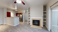 Located in Colorado Springs, CO, this single-floor residence offers a well-designed, open-concept layout finished with neutral tones and durable wood-style flooring throughout. The living area serves as the heart of the home, anchored by a tile-surround fireplace with a classic white mantel and flanked by built-in shelving for display and storage. A ceiling fan overhead and sliding glass doors leading to a private balcony—with views of the surrounding Colorado landscape—complete the inviting atmosphere. The kitchen is thoughtfully appointed with rich cherry-toned cabinetry, granite countertops, stainless steel appliances including a refrigerator and microwave, and a breakfast bar that opens to the living space. Two well-sized bedrooms each feature ceiling fans and generous natural light. The primary bedroom includes access to a walk-in closet with wire shelving. Both bathrooms are finished with granite-topped vanities and cherry wood cabinetry; one features a tub/shower combination, while the other is equipped with accessibility-friendly grab bars. A dedicated laundry area houses a full-size washer and dryer with overhead wire shelving for additional storage. Clean, modern finishes and a functional floor plan make this Colorado Springs residence a comfortable and practical home.