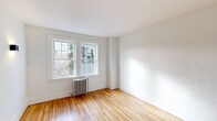 Located at 35 Prospect St in Bristol, CT, this single-floor, two-bedroom, one-bathroom unit offers a thoughtfully laid-out living space with a clean, modern aesthetic rooted in classic architectural details. Warm hardwood floors run throughout, lending continuity and a bright, natural feel to every room.

The primary bedroom is a well-proportioned retreat featuring multiple double-hung windows that frame leafy outdoor views and flood the room with natural light. A classic cast-iron radiator adds vintage character, and wall sconces provide warm ambient lighting. The second bedroom is equally bright, with its own window and radiator, and features rich, dark-stained wood doors that add a charming contrast to the white walls.

The galley-style kitchen has been thoughtfully renovated with two-tone cabinetry, marble-look countertops, a built-in cooktop, microwave, stainless steel refrigerator, and an in-unit washer — all within an efficient, well-organized layout. A window at the end of the kitchen keeps the space bright and airy.

The bathroom is a standout highlight, showcasing floor-to-ceiling marble-look tile, a deep soaking tub, matte black fixtures, a modern floating vanity with an integrated sink, and a natural light window — a striking blend of contemporary design and timeless elegance. A hallway connects all rooms, completing this cohesive and well-appointed residence.