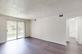 Located at 2111 Benson Gardens Blvd in Omaha, Nebraska, this 2-bedroom, 1-bathroom unit offers a practical and well-organized single-floor layout. Dark hardwood-style flooring runs consistently throughout the space, providing a warm contrast against the crisp white walls and textured ceilings found in every room.

The living room is the focal point of the unit, featuring a sliding glass door that opens to a private balcony with outdoor views of surrounding greenery, allowing natural light to fill the space. The kitchen is well-appointed with ample white cabinetry extending to the ceiling, a double-basin sink, white appliances including a range and dishwasher, and a window fitted with blinds for added light control.

Both bedrooms are comfortably sized, each featuring windows with blinds that bring in natural light, textured ceilings, and the same consistent flooring found throughout the unit. The primary bedroom offers a generous footprint with good proportions. The full bathroom is finished in an all-white palette, complete with a tub/shower combo, a vanity with storage below, and matching flooring. A connecting hallway ties all rooms together, contributing to an efficient and functional floor plan.