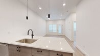 Located at 146 S Wayfinder Ave in Meridian, Idaho, this single-story space presents a clean, contemporary design defined by a bright, neutral palette and high-quality finishes throughout. The open-concept layout seamlessly connects the kitchen and living area, creating a spacious, functional flow ideal for everyday living.

The kitchen serves as a central highlight, anchored by a large island with a crisp white quartz countertop, an undermount stainless steel sink, and a matte black gooseneck faucet. Cabinetry features a warm wood-tone finish with sleek black hardware, complemented by light gray upper cabinets and a subtle tile backsplash. Stainless steel appliances—including a French door refrigerator, electric range, microwave, and dishwasher—complete the well-appointed cooking space. Matte black pendant lights hang above the island, adding a modern design accent.

The living area extends naturally from the kitchen, featuring light wood-look flooring, recessed lighting, and access to an exterior door. Bedroom spaces offer neutral carpet, ample natural light from well-placed windows, and a calm, restful atmosphere. The bathroom is finished with light wood-tone flooring, a frameless sliding glass shower enclosure with matte black framing, and coordinating fixtures, maintaining the cohesive modern aesthetic found throughout the space.