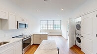 Located at 179 Chelsea Ave in Long Branch, NJ, this thoughtfully designed one-bedroom, one-bathroom unit offers a clean, modern aesthetic with high-quality finishes throughout. Warm hardwood-style flooring flows seamlessly across the entire single-floor layout, creating a cohesive and inviting atmosphere.

The kitchen is a standout feature, outfitted with crisp white shaker cabinetry, striking marble-look quartz countertops, and a full suite of stainless steel appliances including a range, over-the-range microwave, dishwasher, and refrigerator. A central island provides additional prep and dining space, while large multi-pane windows flood the area with natural light and offer views of the surrounding neighborhood.

The bedroom is a comfortable, well-proportioned retreat featuring a large built-in closet with custom shelving, hanging rods, and integrated drawers — offering excellent organization and storage. A wide window with a roller shade provides natural light and a neighborhood view.

The bathroom is finished with neutral large-format tile flooring, a white shaker vanity with quartz countertop, matte black hardware accents, and a backlit mirror, combining functionality with a refined contemporary style.

A hallway connects the living spaces efficiently. Throughout the unit, clean white walls, recessed lighting, and matte black hardware details contribute to a polished, modern character.