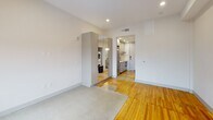 Located in the heart of Richmond, Virginia, this thoughtfully designed single-floor unit at 703 E Main St blends modern finishes with warm, characterful details. The main living area showcases a striking combination of polished concrete and rich hardwood flooring, creating a dynamic visual contrast that adds depth and texture to the open layout. Crisp white walls and recessed lighting throughout keep the space feeling bright and airy.

The kitchen is outfitted with sleek gray cabinetry, stainless steel appliances, and clean countertops, offering a functional and contemporary workspace. A dedicated in-unit laundry area adds everyday convenience. A mirrored wardrobe unit in the main area enhances the sense of space while providing practical storage.

The bathroom features elegant marble-style tile spanning both the walls and floor, complemented by matte black hardware accents and a glass-enclosed shower, lending a polished, upscale feel. The bedroom area is generously proportioned with warm hardwood floors and two large windows fitted with roller shades, framing expansive views of the Richmond cityscape — a standout feature that fills the room with natural light and a strong sense of place. The overall ambiance is clean, modern, and move-in ready.