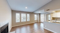 Located at 301 Martha Layne Collins Blvd in Highland Heights, Kentucky, this 2-bedroom, 2-bathroom home offers a thoughtfully designed single-floor layout. The open-concept living room is a standout space, featuring vaulted ceilings, a tile-surround fireplace, and an abundance of natural light streaming through multiple double-hung windows that frame views of the surrounding neighborhood. Warm hardwood-style flooring flows throughout the main living areas, complementing the neutral taupe wall tones. The galley-style kitchen is efficiently organized with white cabinetry, stone-look countertops, and a full suite of stainless steel appliances, including a range, microwave, and refrigerator. A dedicated laundry area with a full-size washer and dryer adds everyday convenience. The spacious primary bedroom features plush carpeting, a ceiling fan, a walk-in closet with wire shelving, and direct access to a private bathroom. The second bedroom is equally comfortable, with carpeted flooring, a ceiling fan, and a bright window. A hallway connects the bedrooms and bathrooms, maintaining a practical and efficient flow throughout the home. A staircase provides additional access, rounding out this well-equipped residence.