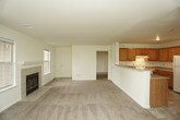 This single-floor residence offers a thoughtfully arranged layout that balances comfort and functionality throughout its key living areas. The spacious living room serves as the heart of the home, centered around a tile-surround fireplace flanked by large windows that invite natural light. A glass-paned exterior door provides direct outdoor access, adding to the room's open, airy feel. Adjacent to the living area, an open-concept space connects to the kitchen via a raised breakfast bar with a dark countertop, creating a natural flow between the two zones. The kitchen is well-equipped with warm oak cabinetry, light countertops, a white appliance suite including a range and refrigerator, and durable tile flooring. The bedrooms are carpeted in neutral tones and feature windows for natural light and individual closets for ample storage. The bathrooms are finished with tile flooring, one offering a full tub-and-shower combination with a grab bar and a built-in shelving closet nearby, while the other provides a vanity with a medicine cabinet mirror. Throughout the residence, a consistent palette of soft neutral tones and clean white trim contributes to a bright, move-in-ready ambiance.