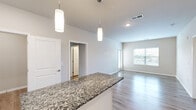 Located at 101 NW Mock Ave in Blue Springs, MO, this single-story, 3-bedroom, 3-bathroom home offers a thoughtfully designed layout with modern finishes throughout. The open-concept kitchen is a standout feature, showcasing white shaker cabinetry, granite countertops, a large center island with pendant lighting, and a full suite of stainless steel appliances, including a refrigerator, range, microwave, and dishwasher. A classic white tile backsplash and light wood-style flooring complete the contemporary look. The kitchen flows seamlessly into the living room, which is filled with natural light from large windows. The bedrooms include both carpeted and hard-surface flooring options, with ceiling fans and ample natural light. The primary bedroom features its own en-suite bathroom with a double-sink granite vanity, wood-style flooring, and a glass-enclosed walk-in shower with elegant tile surround. A second full bathroom offers a tub-shower combo with matching tile and a granite vanity. Five closets provide generous storage throughout. A dedicated laundry room comes equipped with a full-size washer and dryer, plus wire shelving above for added convenience.
