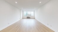 This thoughtfully designed single-floor unit at 4805 offers a clean, contemporary aesthetic throughout its well-proportioned layout. Light hardwood flooring flows seamlessly across the living areas and bedrooms, complementing the crisp white walls and recessed lighting that create a bright, airy atmosphere.

The open-plan living and dining area is generously sized, anchored by large windows that frame sweeping city skyline views, flooding the space with natural light. A wall-mounted HVAC unit ensures year-round comfort.

The modern kitchen is outfitted with full-height light wood cabinetry, a marble-look quartz backsplash and countertops, a stainless steel dishwasher, range, and refrigerator — offering both style and functionality.

Two bathrooms provide refined finishes throughout. The primary bathroom features floor-to-ceiling marble-look tile in a glass-enclosed walk-in shower, matte black fixtures, and a quartz vanity. The second bathroom offers a floating wood vanity with quartz countertop, an undermount sink, matte black hardware, and a large framed mirror.

The additional rooms are versatile and well-lit, each benefiting from the same hardwood flooring, recessed lighting, and clean minimalist design, making the space move-in ready and adaptable to a variety of uses.