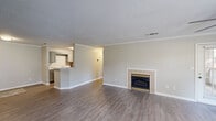 Located at 117 Royal Dr in Madison, Alabama, this single-story, 4-bedroom, 2-bathroom home offers a well-designed layout with a comfortable and functional living environment. The living room serves as the heart of the home, highlighted by a classic tile-surround fireplace with brass accents and durable hardwood-style flooring that flows seamlessly throughout the main areas. Crown molding and a textured ceiling add a refined architectural touch, while the open sightlines to the kitchen create an inviting, connected feel. The kitchen is well-appointed with gray cabinetry, light stone-look countertops, a full suite of black appliances including a refrigerator, electric range, and built-in microwave, plus a peninsula that opens to the living area. The bedrooms feature plush carpeting, natural light from windows with blinds, and generous closet space, including a walk-in closet with wire shelving. The bathrooms are finished with gray vanities, light countertops, and tiled shower/tub combos with wood-style flooring. A dedicated laundry room with wire shelving and side-by-side washer and dryer hookups adds everyday convenience. A separate bedroom wing offers a bright, open room with a ceiling fan and multiple windows, ideal as a primary suite or flex space.